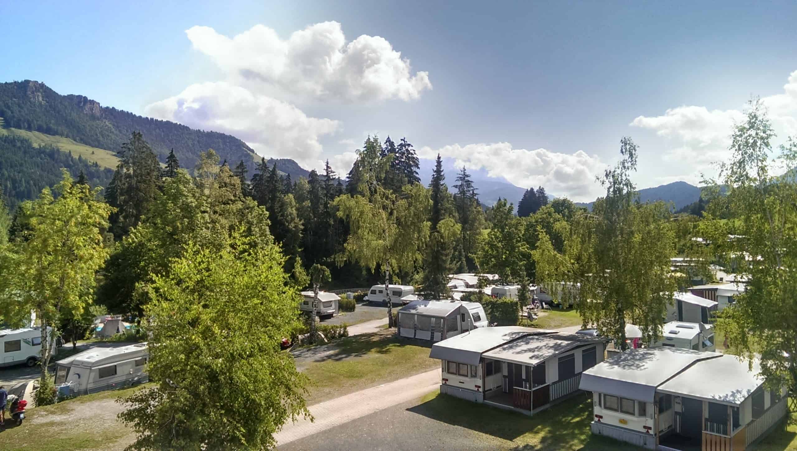 Auf dem Bild wird ein Campingplatz gezeigt. Man sieht Wohnwagen in der Natur